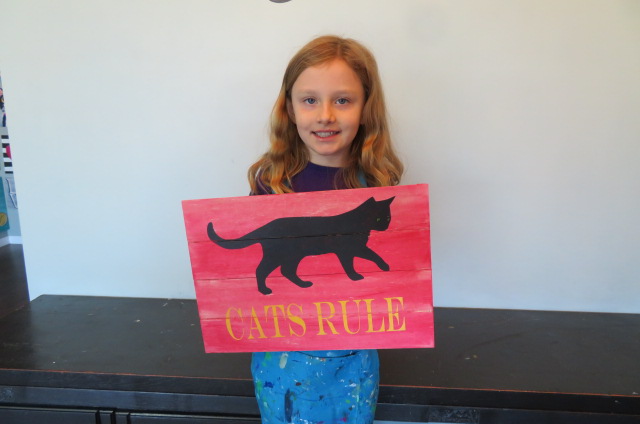 girl holding painted wood sign