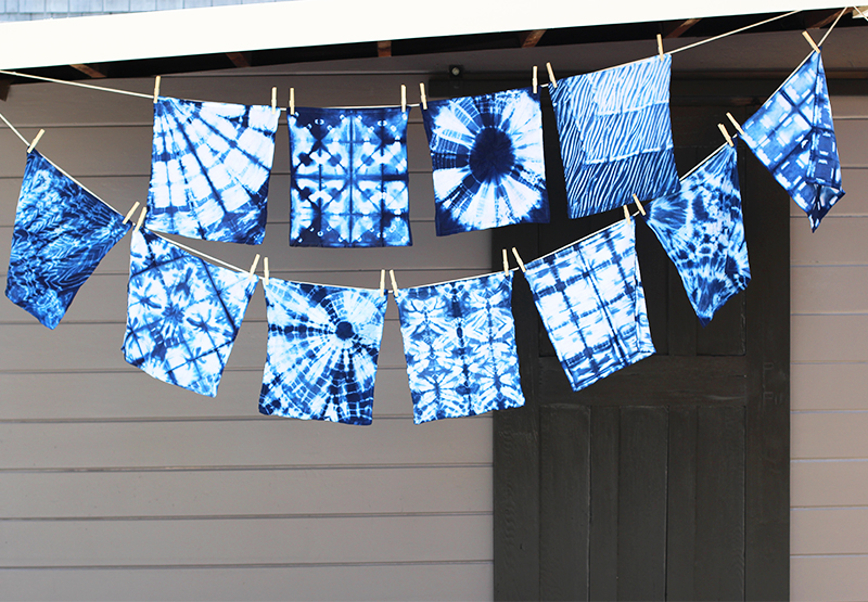 Blue and white tie dyed fabric samples hanging from clothesline 
