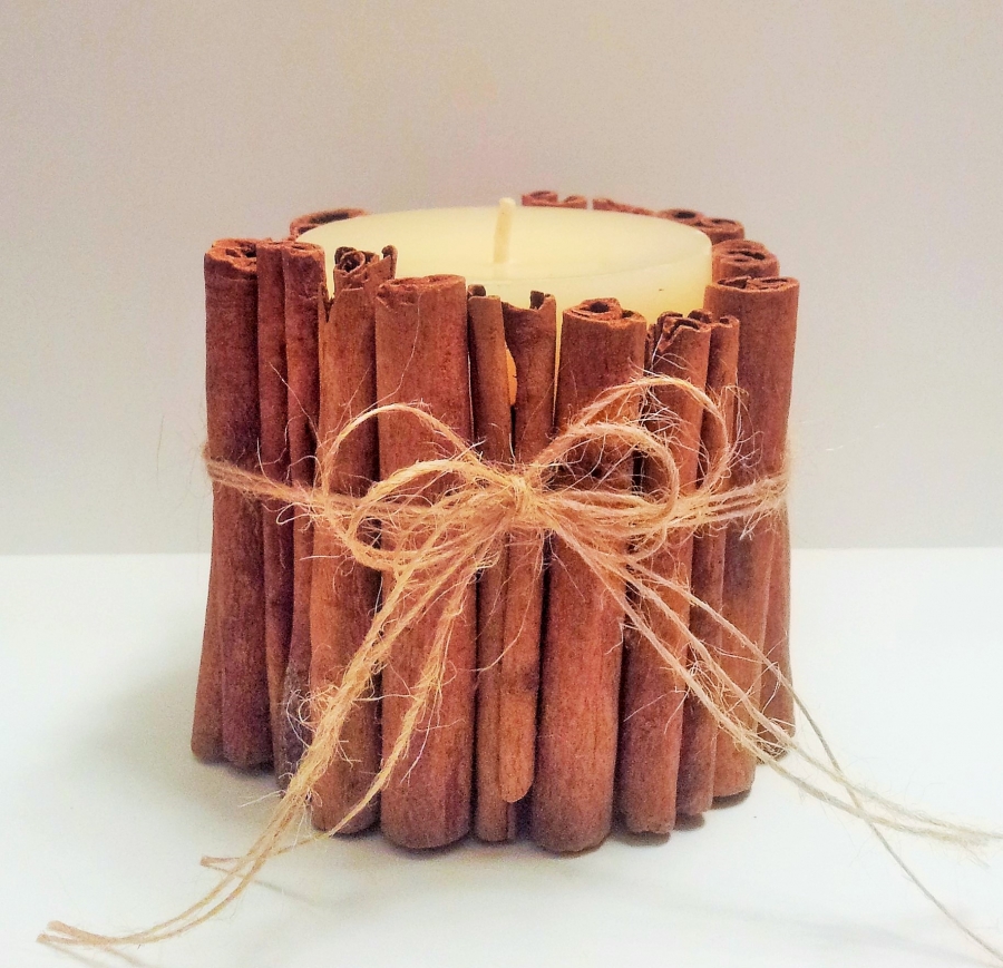 festive candle with cinnamon sticks tied around it 