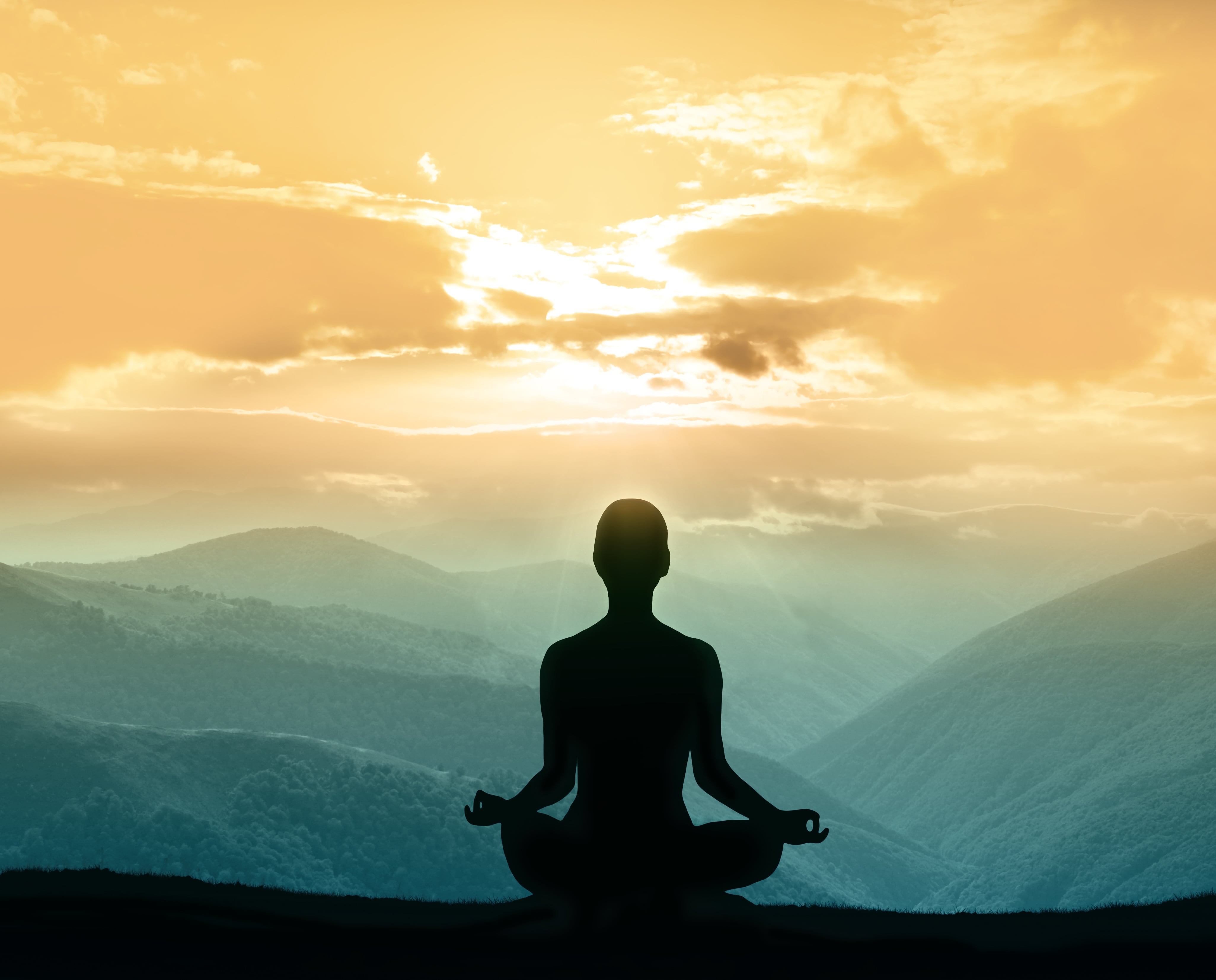 silhouette of person meditating in mountains