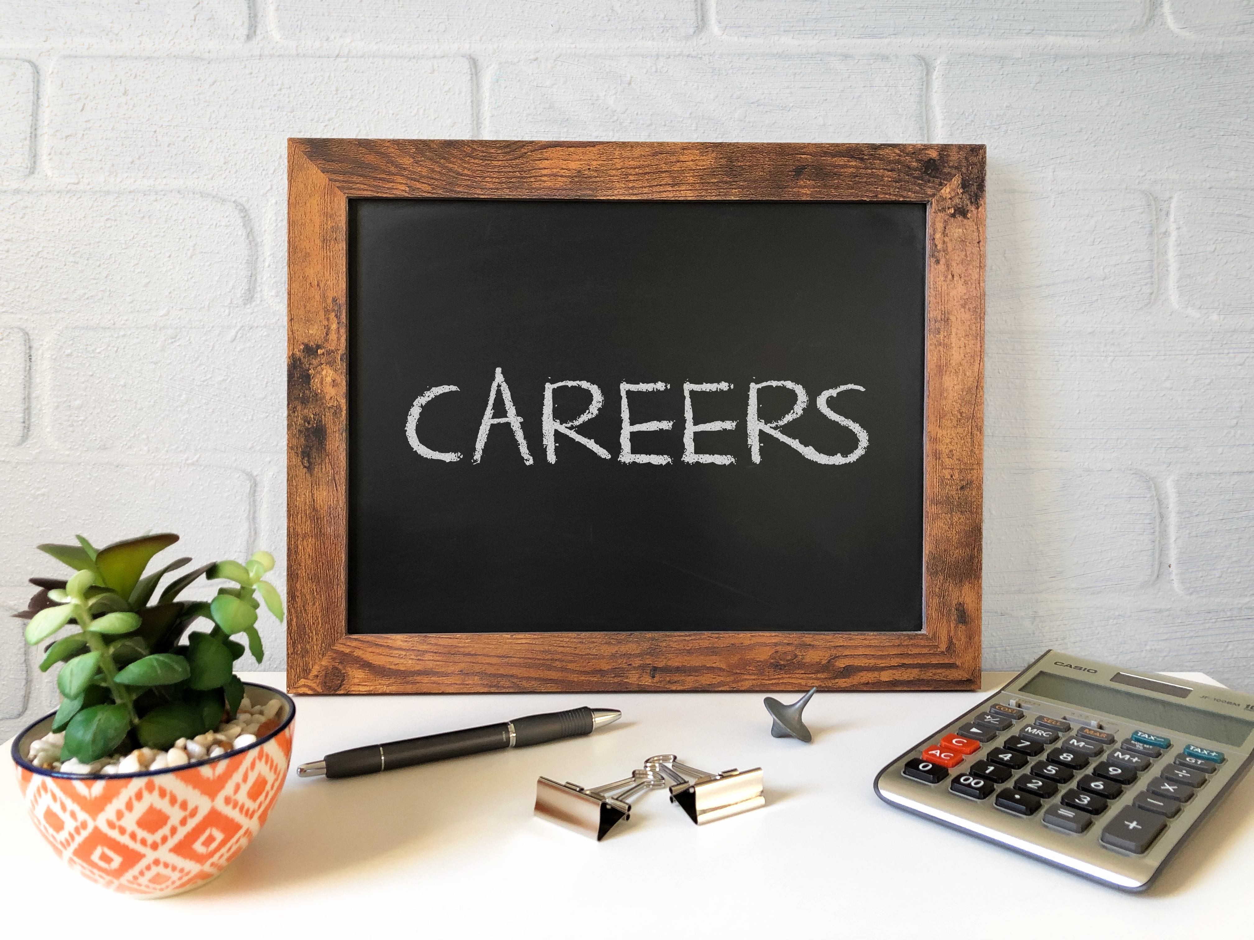 Blackboard with word "Careers" on table with plant and calculator