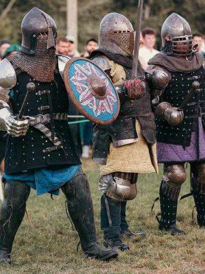 Three people dressed as medieval knights with swords and shields.